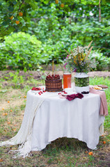 Summer picnic on nature, with a delicious chocolate cake, compote, berries, wild flowers