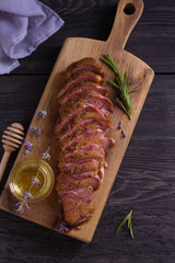 Sliced duck breast, lavender honey and rosemary on serving board