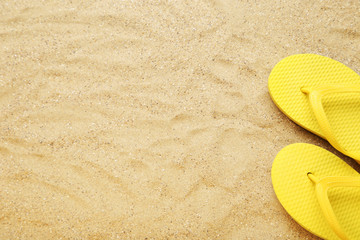 Fototapeta na wymiar Yellow flip flops on beach sand