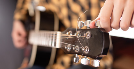 The young man tuning the electric guitar.