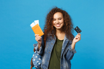 Young african american girl teen student in denim clothes, backpack hold pass isolated on blue wall background studio portrait. Education in high school university college concept. Mock up copy space.