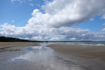 Poland, Gdansk, Baltic Sea - walking people on Jelitkowo beach in cloudy day with amazing dramatic clouds