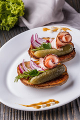 Halves baked potato with pickled cucumber, dill, salo and onion on wooden table