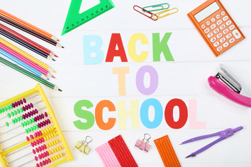 Text Back To School with stationery on white wooden table