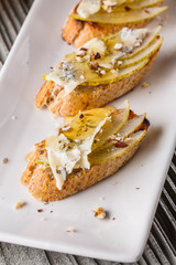 Appetizer bruschetta with pear, honey, walnut and blue cheese on white plate