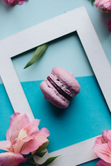 Piece of delicious macaroon on floral background with frame