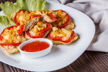 Chicken fillet in a batter with corn, paprika, lettuce and spicy tomato sauce on white plate