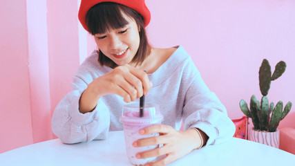 Young asian millennial woman drinking bubble iced tea at the pastel cafe, food and drink concept