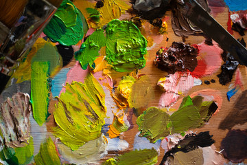 Art studio with a palette full of different colors of oil paint in a table