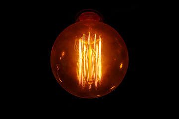 Light bulb with beautiful filament on a dark background
