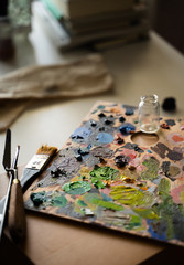 Art studio with a palette full of different colors of oil paint in a table