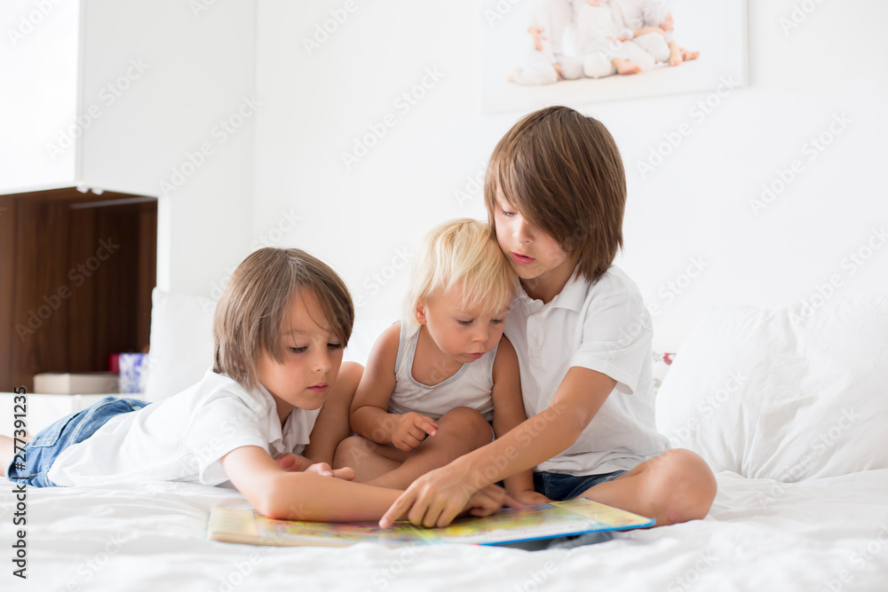 Poster Three brothers, sweet kids, reading a book in bed