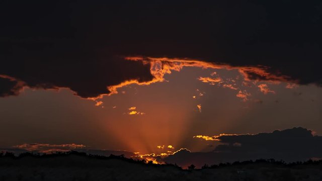 The epic view of the sunset, the delightful red rays through the thunderclouds - a beautiful view of the heavens and the sun. Time lapse