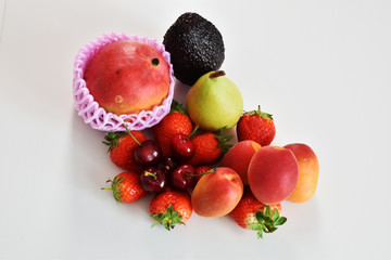 top view of assorted fruits strawberries cherries apricots and avogado on a white background