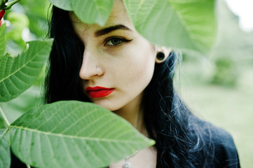 Sensual girl all in black, red lips and earlobe piersing. Goth dramatic woman.