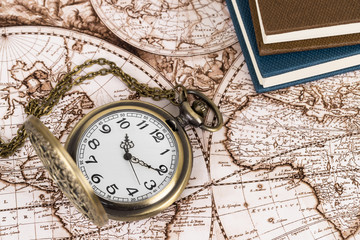 Vintage pocket watch clock on ancient map background with books