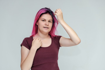 Portrait to the waist of a young pretty girl teenager in a burgundy T-shirt with beautiful purple hair on a white background in the studio. Talking, smiling, showing hands with emotions.