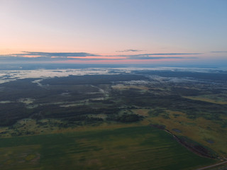 Fototapeta na wymiar View from the height of the quadcopter on the landscape before dawn , fog dissipates in the fields near the forest.