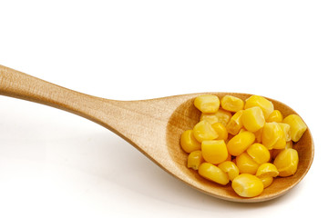 Corn seeds in a wooden spoon isolated on white background