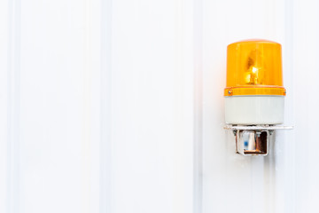White corrugated metal wall texture with yellow emergency light on the right side