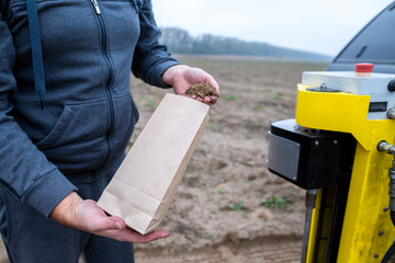 Soil Sampling. An engineer employee of a research laboratory packs a soil sample in a paper package. Automated probe for soil samples taking sample with soil probe sampler.