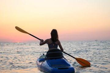 young girl on the kayak greets the dawn of the sun