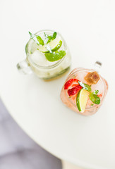 Two lemonade drinks with fresh strawberry, lime and mint in glass.