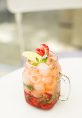 Lemonade drink with fresh strawberry, lime and mint in glass.