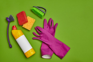 Detergents and cleaning accessories on a green background. Housekeeping concept.