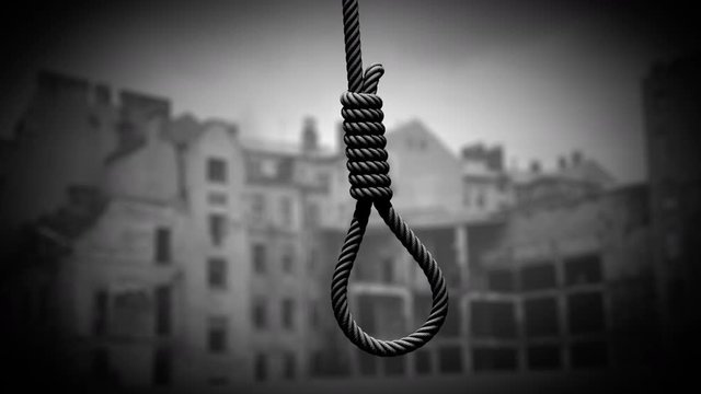 Hangman's noose against the backdrop of a war-torn city. Rope for hanging swings from side to side like a pendulum. Seamless loop 3D animation stylized under black and white newsreel and documentary.