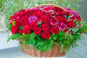 Delivery of a bouquet of flowers in the office. A huge bouquet of roses and peonies in a large basket. Red roses and pink peonies in a brown basket
