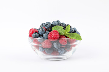 Glass sauceboat with berries isolated on white background