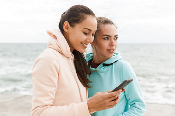 Two pretty smiling fitness women wearing hoodies