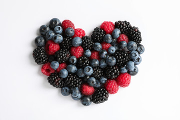 Heart laid out of berries on white background, top view