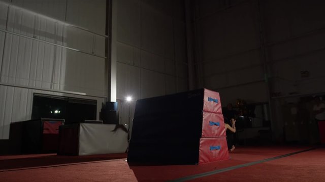 Female athlete doing impressive tumbling on trampolines and gym parcour equipment