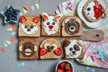 Funny animal faces toasts with spreads, banana, strawberry and blueberry