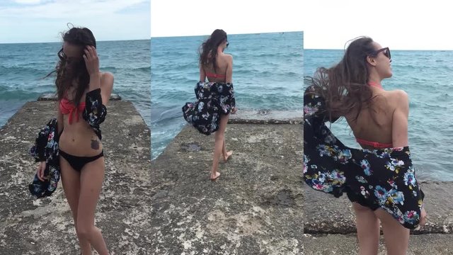 set of vertical mobile phone videos - happy smiling pretty young woman in bikini and light black beach clothes joyfully walks on the pier and wind blowing her hair, slow motion