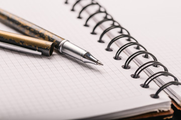 Opened notepad in a cage with an automatic plastic ballpoint pen close-up. toned