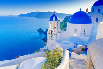 Santorini, Greece. Charming view Oia village on Santorini island. Traditional  famous blue dome church over the Caldera in Aegean sea. Traditional blue and white Cyclades architecture. - obrazy, fototapety, plakaty