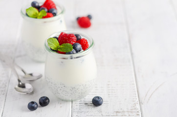 Chia seed pudding with fresh berries on a white wooden table, selective focus.