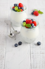 Chia seed pudding with fresh berries on a white wooden table, selective focus.