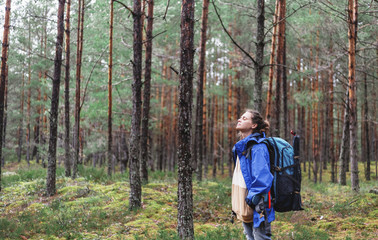 young beautiful woman with hiking backpack in the forest enjoying nature and solitude