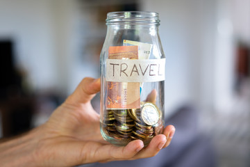 Mão a agarrar frasco de mealheiro etiquetado 