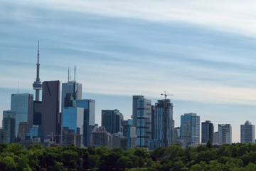 Fototapeta na wymiar Toronto skyline against greenery with mirrored building and construction crane