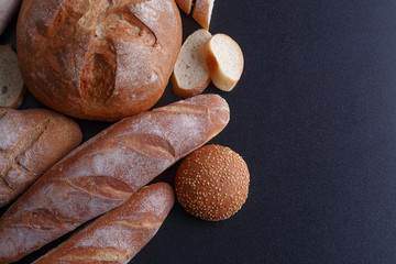 Bakery - gold rustic crusty loaves of bread and buns on black chalkboard background.