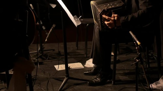 A Bandoneon / harmonica player is practicing for a Argentinian tango music show.