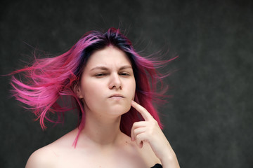 Obraz premium Close-up portrait of a young pretty teen girl with beautiful purple hair on a gray background in the studio. Smiles with emotions