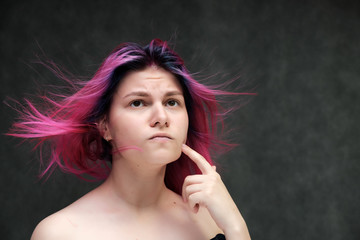 Obraz premium Close-up portrait of a young pretty teen girl with beautiful purple hair on a gray background in the studio. Smiles with emotions