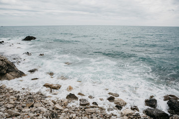 Fototapeta na wymiar Restless sea near the stone coast. Surf. Natural landscape