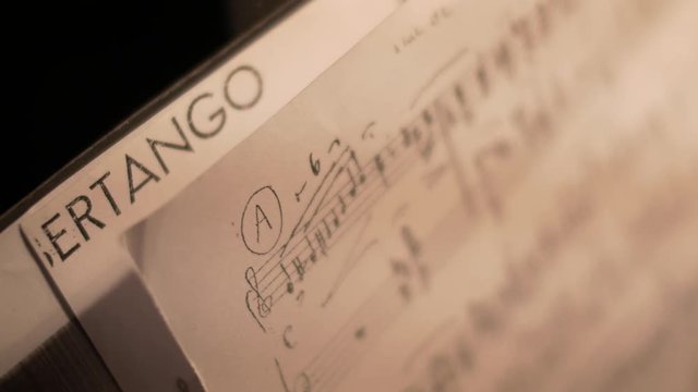 Handheld close-up of a music sheet showing notes of a tango piece.